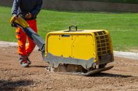 bauarbeiter-der-mit-einer-vibrationsplatte-auf-der-strasse-arbeitet